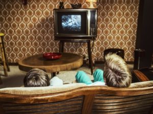 53551237 - two boys watching television at home in 50's style, shot from behind